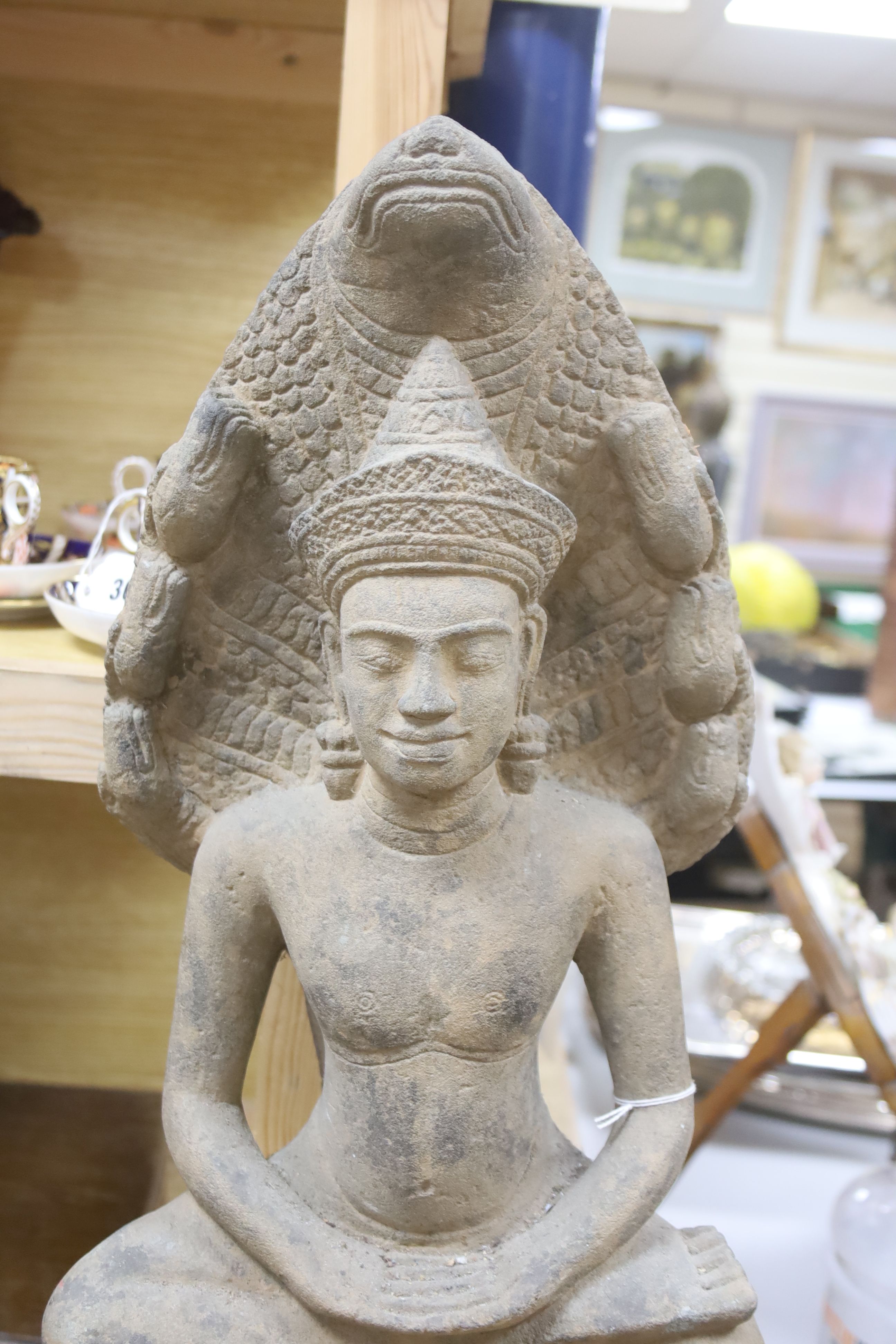 A large stone figure in the style of a Cambodian Buddha, on stand, height 68cm